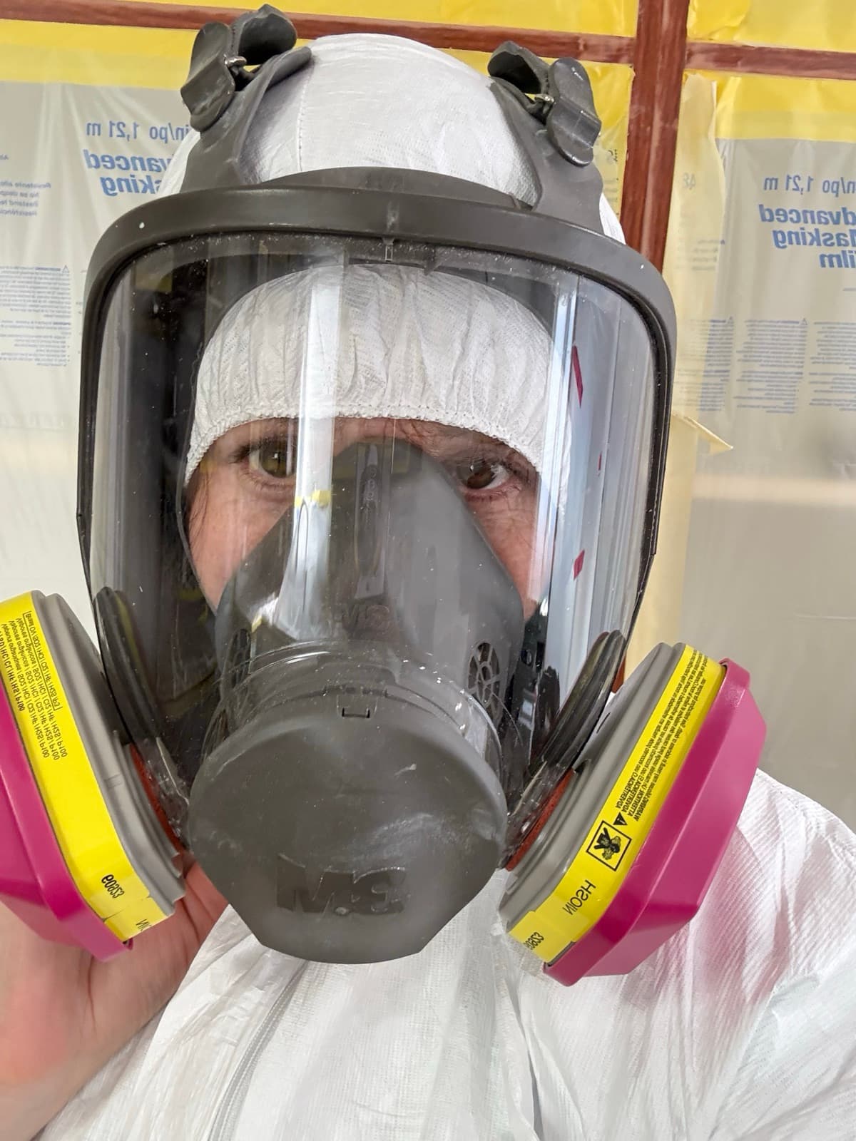 Anna in a full respirator and protective suit while filming on a work site